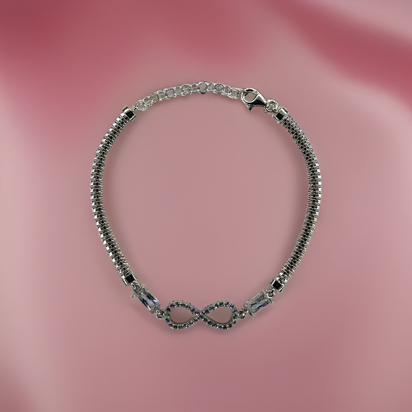 Silver infinity charm bracelet on pink.
