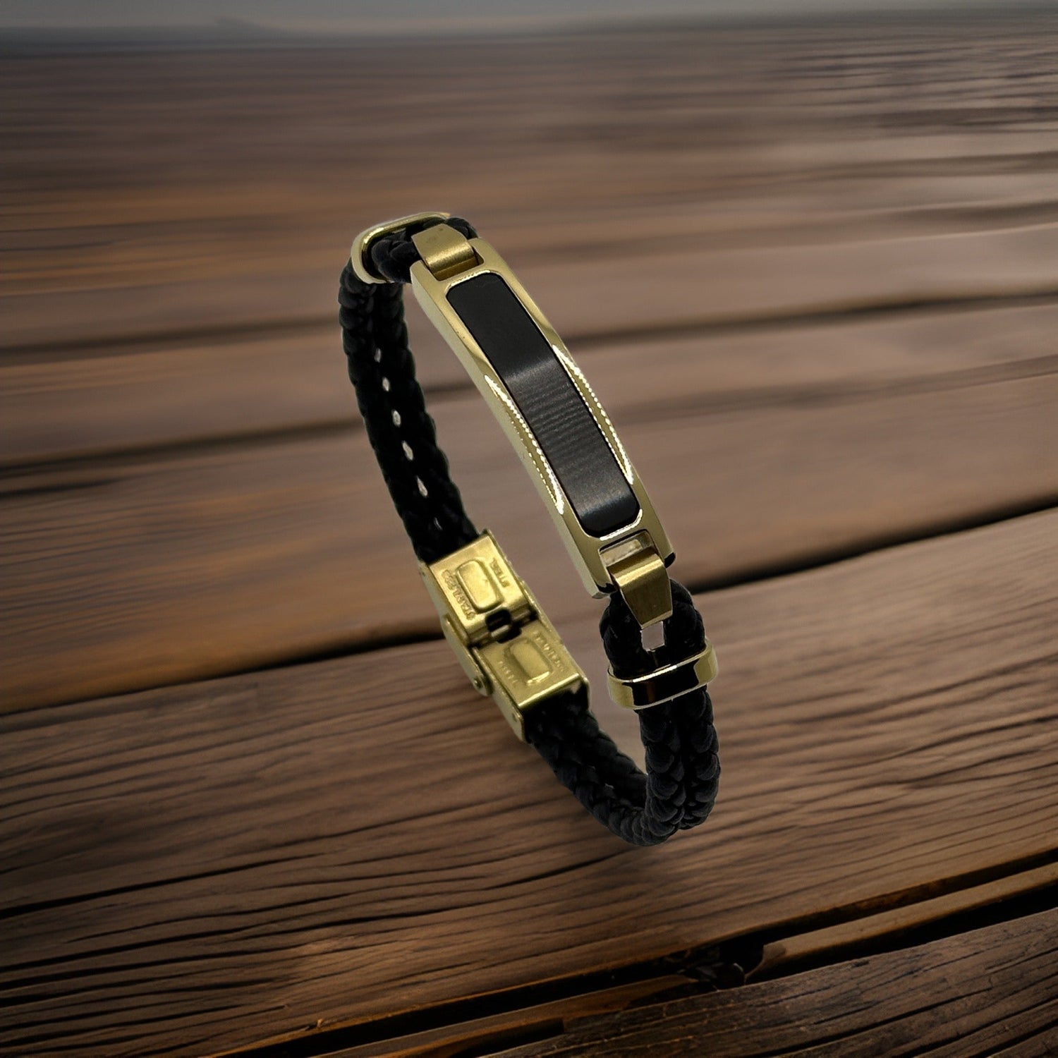 Black and gold-plated leather bracelet, woven design, rests on wooden surface.